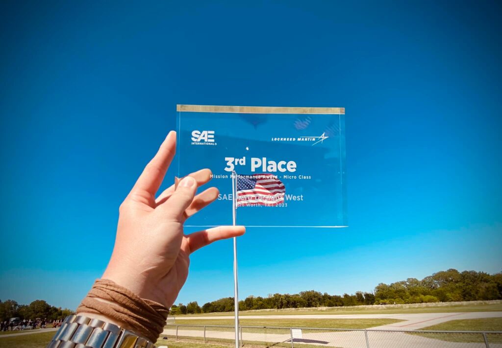 Zdjęcie pokazujące szklaną przezroczystą statuetkę, która była nagrodą za zajęcie 3 miejsca w zawodach SAE Aero Design West 2023