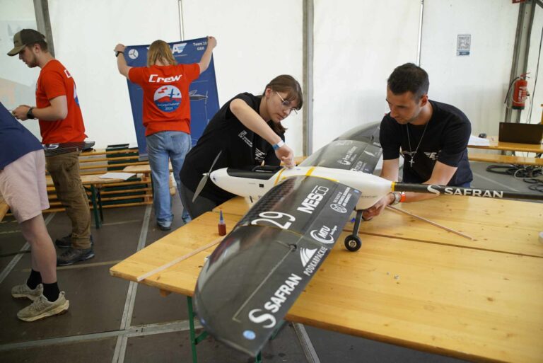 Zdjęcie przedstawia studentkę K.N. EUROAVIA Rzeszów, poprawiającą model EA-02 Nightlight przed zawodami oraz studenta, który na to patrzy i podziwia