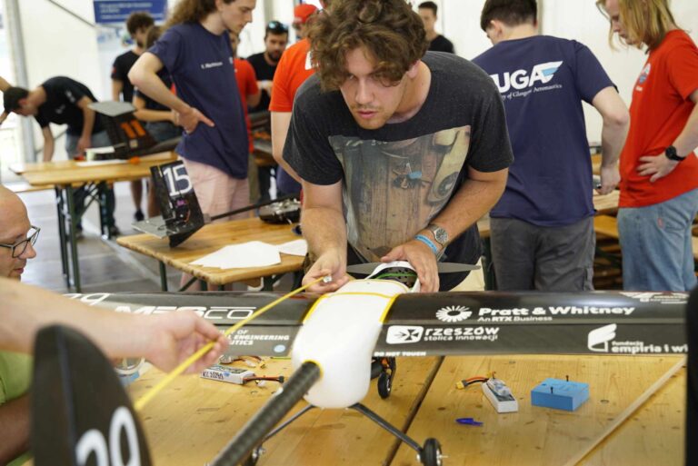 Zdjęcie przedstawia studenta K.N. EUROAVIA Rzeszów, który pomaga inspektorowi technicznemu sprawdzić, czy samolot spełnia wymogi długości na zawodach ACC2024